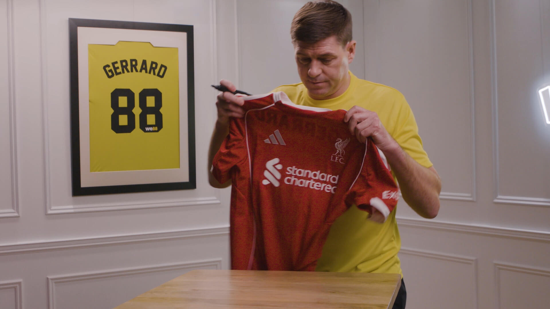 BX99 26/27 Global Brand Ambassador Usain Bolt holding up a red Liverpool jersey to sign during a behind-the-scenes shoot
