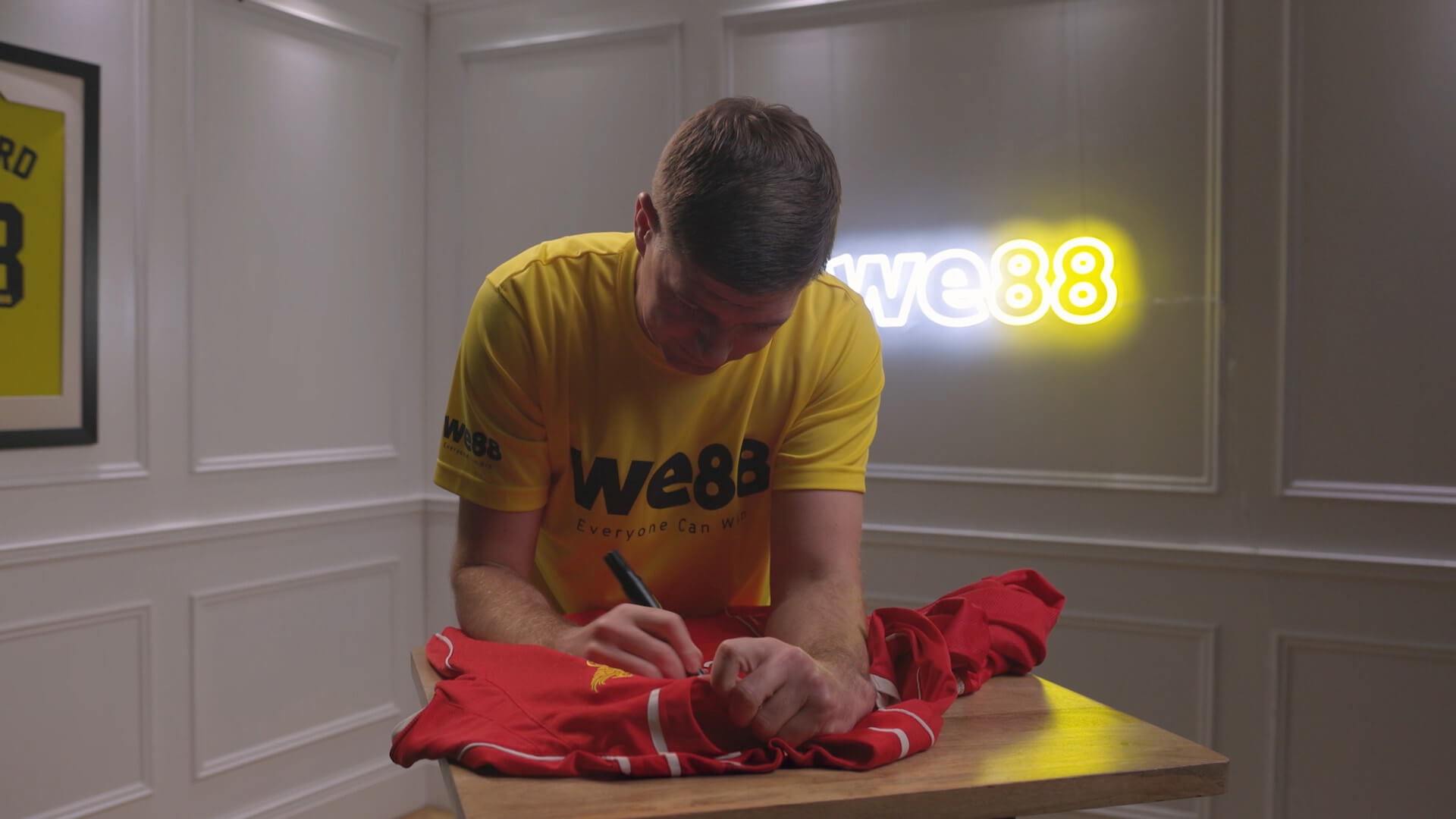 BX99 26/27 Global Brand Ambassador Usain Bolt signing a red football jersey during an exclusive behind-the-scenes session